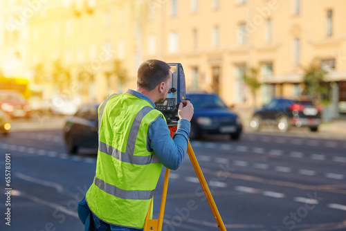 Survey engineer work with theodolite, measure vertical and horizontal angles. Unrecognizable man with electronic, optical instrument, total station theodolite used for surveying. photo