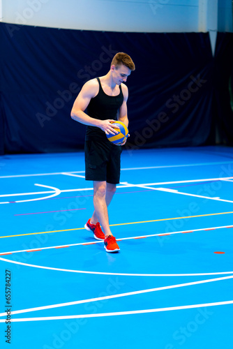 young pumped up guy sportsman prepares to serve the ball during a volleyball game or match