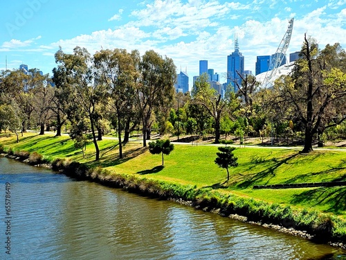 Green trees and grass by the Yarra River with city buildings in the background. Melbourne Victoria, Australia.