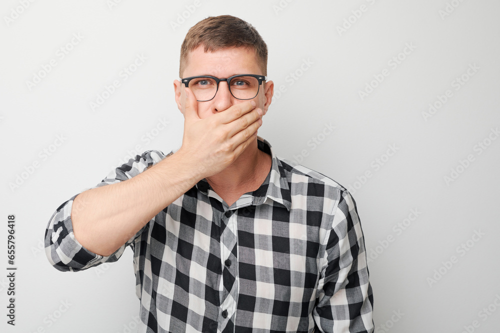 Portrait of man covering his mouth with hand isolated on white studio background. Bad breath concept, sweat smell. Portrait of man covering his mouth with hand isolated on white studio background. Bad breath concept, sweat smell.
