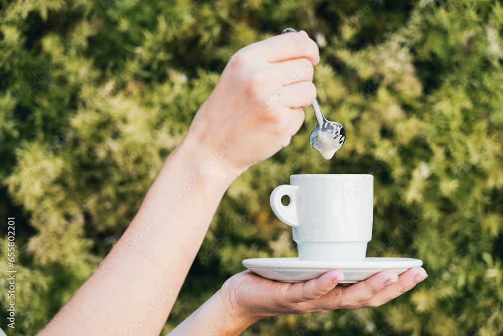 woman holding a cup of coffee with both hands on green vegetable texture background woman holding a cup of coffee with both hands on green vegetable texture background