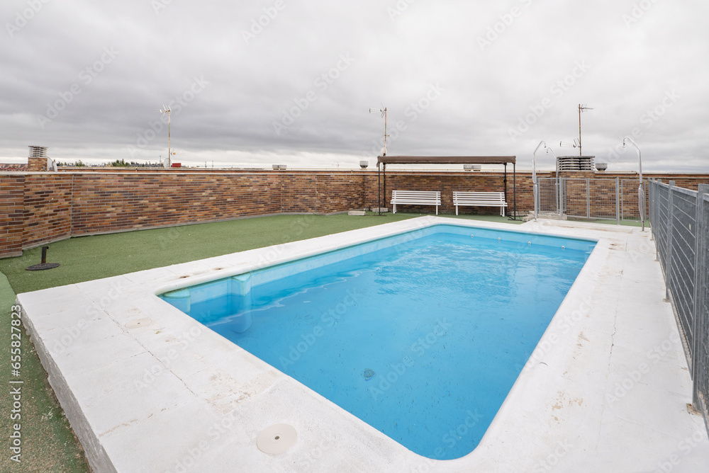 Swimming pool located on the penthouse floor of a residential building with artificial grass surfaces