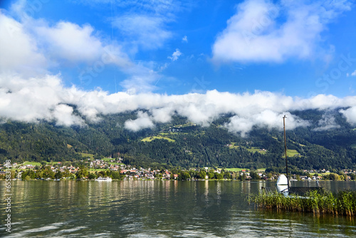 Lake Ossiacher See, Ossiach, Carinthia, Austria. Beautiful summer mountain landscape. Alpine lake surrounded by mountains, slopes of which are covered with forest and white clouds photo