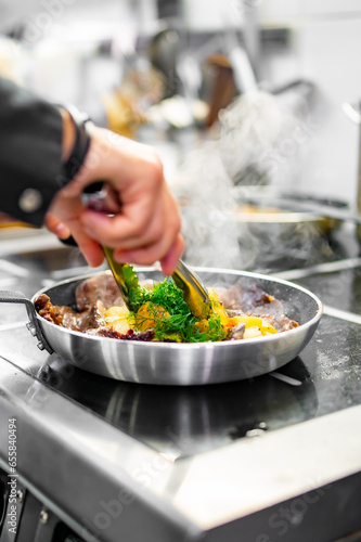 Chef cook hand cooking potato and meat food in pan at the restaurant kitchen