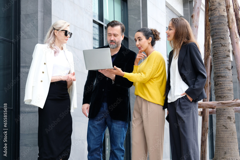 Business men and women stand with laptops and discuss business plans. Business men and women stand with laptops and discuss business plans.