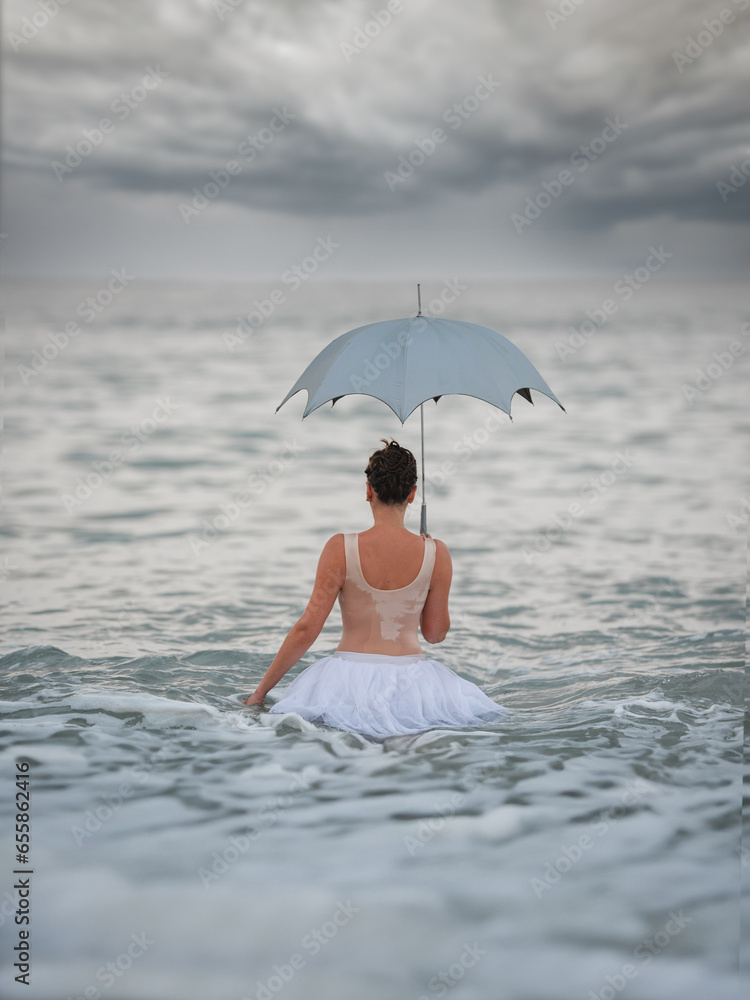 Fototapeta premium A ballerina with gold goes into the sea. Art concept.
