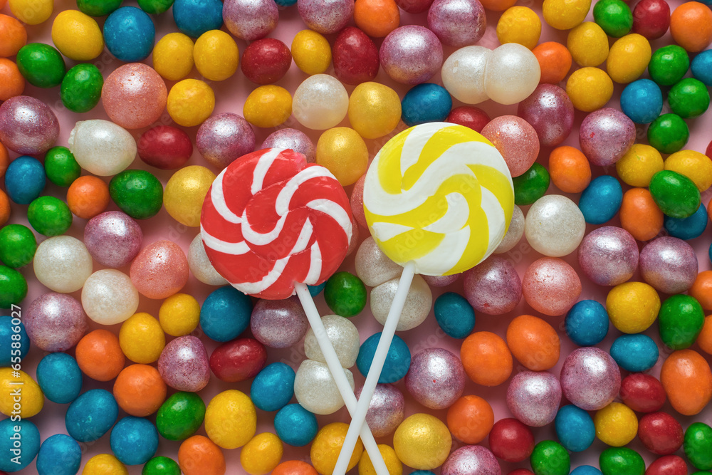 Two lollipops on a stick on a background of colorful candy balls. The concept of sweets.