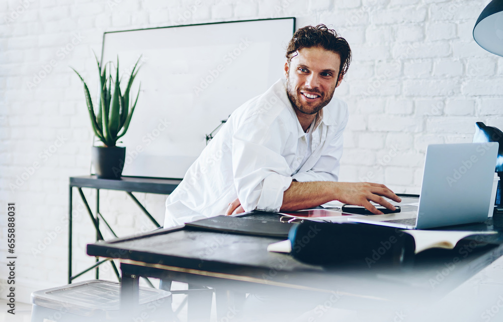 Cheerful caucasian male freelancer enjoying remote job in modern designed coworking space Cheerful caucasian male freelancer enjoying remote job in modern designed coworking space