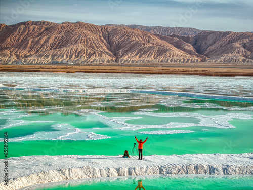 A photographer standing at the emerald salt lake at Mangya, Qinghai province, China. photo