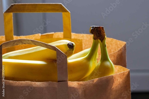 bananas in a paper bag. a bag of groceries in the room on the table. photo