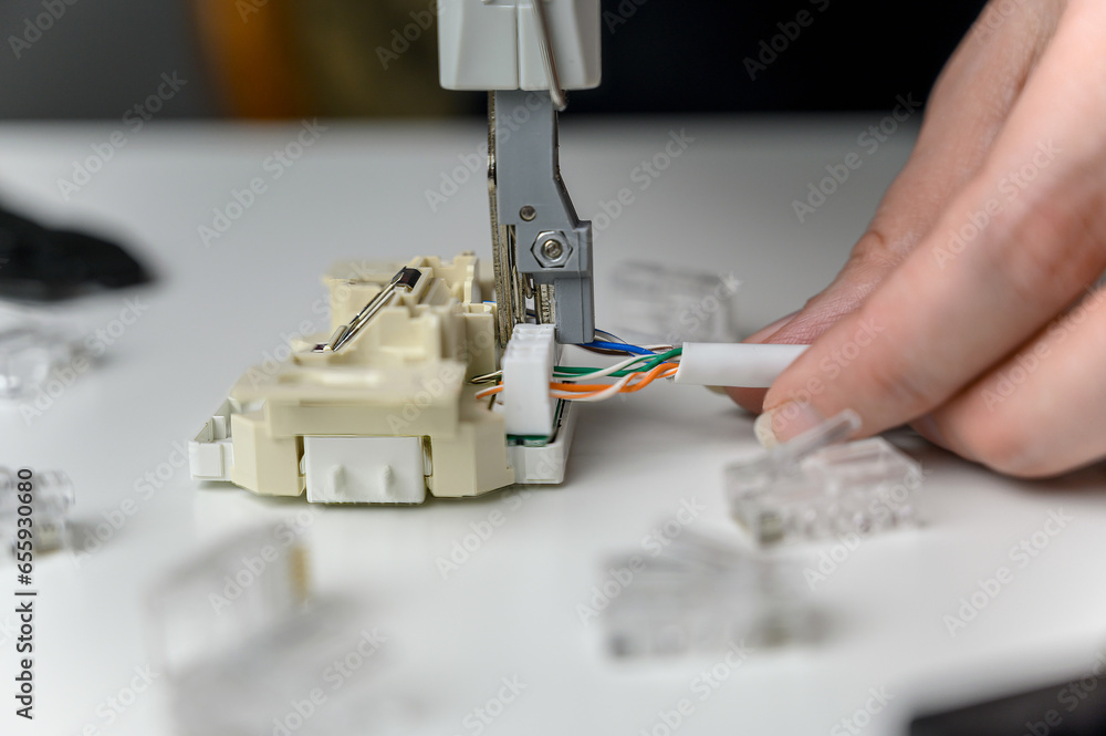 Manual crimping of the network cable. Installation of Internet or telephone line cables using a crimping device.