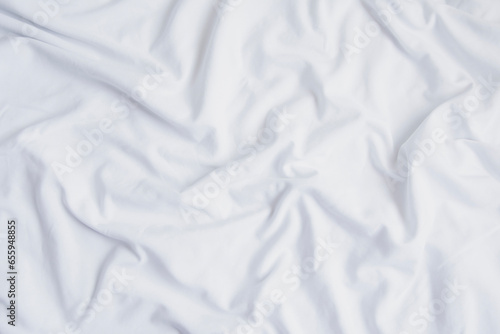 Crumpled white sheet seen from above. White fabric texture and background