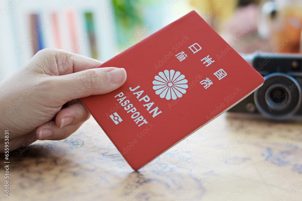 woman hand holds a red Japanese passport with a world map. woman hand holds a red Japanese passport with a world map.