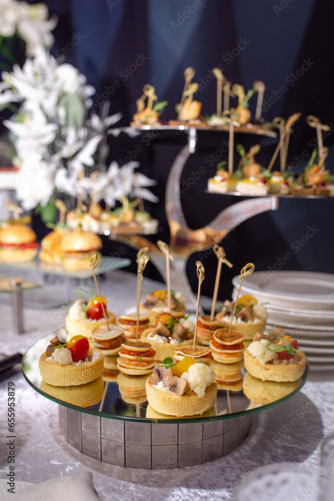 various canapes and drinks on the buffet table on a stand