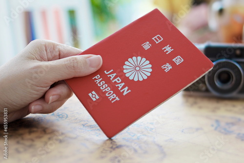 woman hand holds a red Japanese passport with a world map.