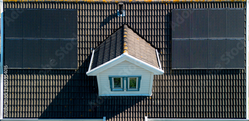 Solar panels on a pitched roof of a wooden white house. Array of pv-panels to gather solar energy