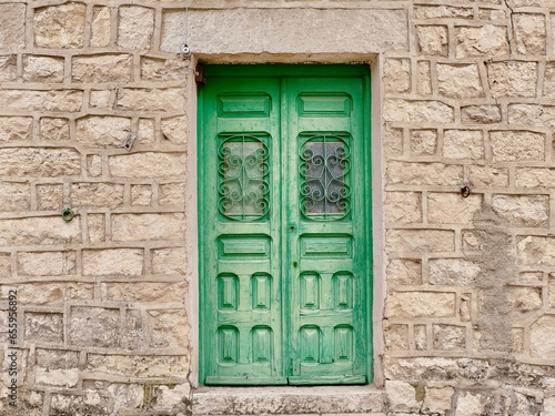 Vintage village door of faded green colour on stone wall in Patones, Madrid community, Spain. Wooden cosy front door