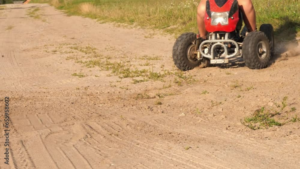 A child makes a sharp turn on an ATV, kicking up dust and sand from the road. The wheels of the ATV slip on the sand, raising dust and sand. A child boy enjoys riding an ATV. A child makes a sharp turn on an ATV, kicking up dust and sand from the road. The wheels of the ATV slip on the sand, raising dust and sand. A child boy enjoys riding an ATV.