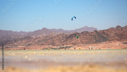Surfers on the kiteboard with colored parafoil wings catching the flow of wind. Kitesurfing in Dahab lagoon. Best Kiteboarding Spots Worldwide photo