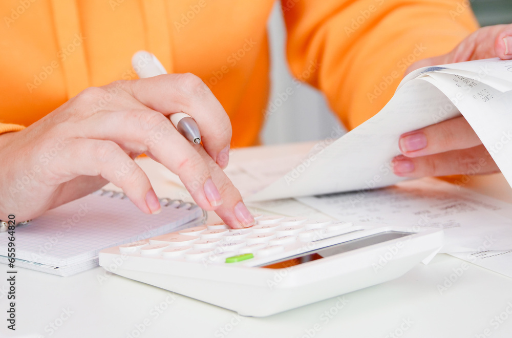 Inflation. Woman uses calculator to calculate expenses for shopping. Receipts and household expenses