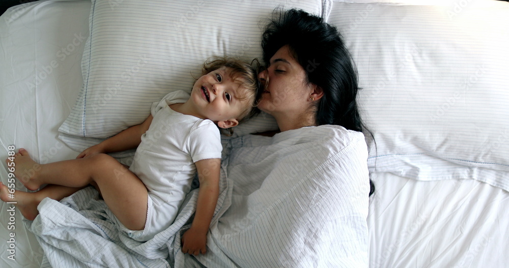 Mother cuddling with baby in morning in bed together, top view Mother cuddling with baby in morning in bed together, top view