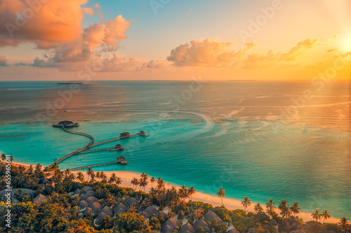 Aerial sunset of beautiful Maldives paradise tropical beach. Amazing colorful sea sky bay water, palm trees sandy beach. Luxury villas resort, travel vacation destination. Best popular landscape view