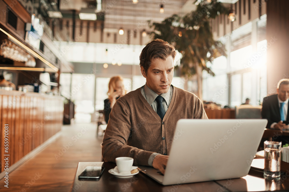 Happy young caucasian businessman using a laptop in a cafe