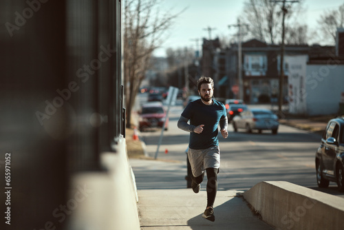 Young and athletic caucasian man jogging on a bridge in the city