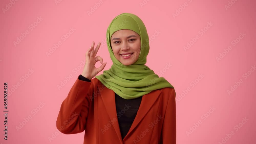 Medium-sized isolated video capturing an attractive young woman wearing a hijab, veil. She is showing an OK gesture, recommending the product. Medium-sized isolated video capturing an attractive young woman wearing a hijab, veil. She is showing an OK gesture, recommending the product.
