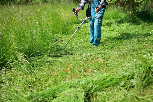 Obraz na płótnie The gardener mows the grass in a modern way with a petrol mower w salonie