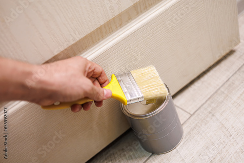 In hand is a paint brush for painting doors and repairs. Repair staining the doors with paint.