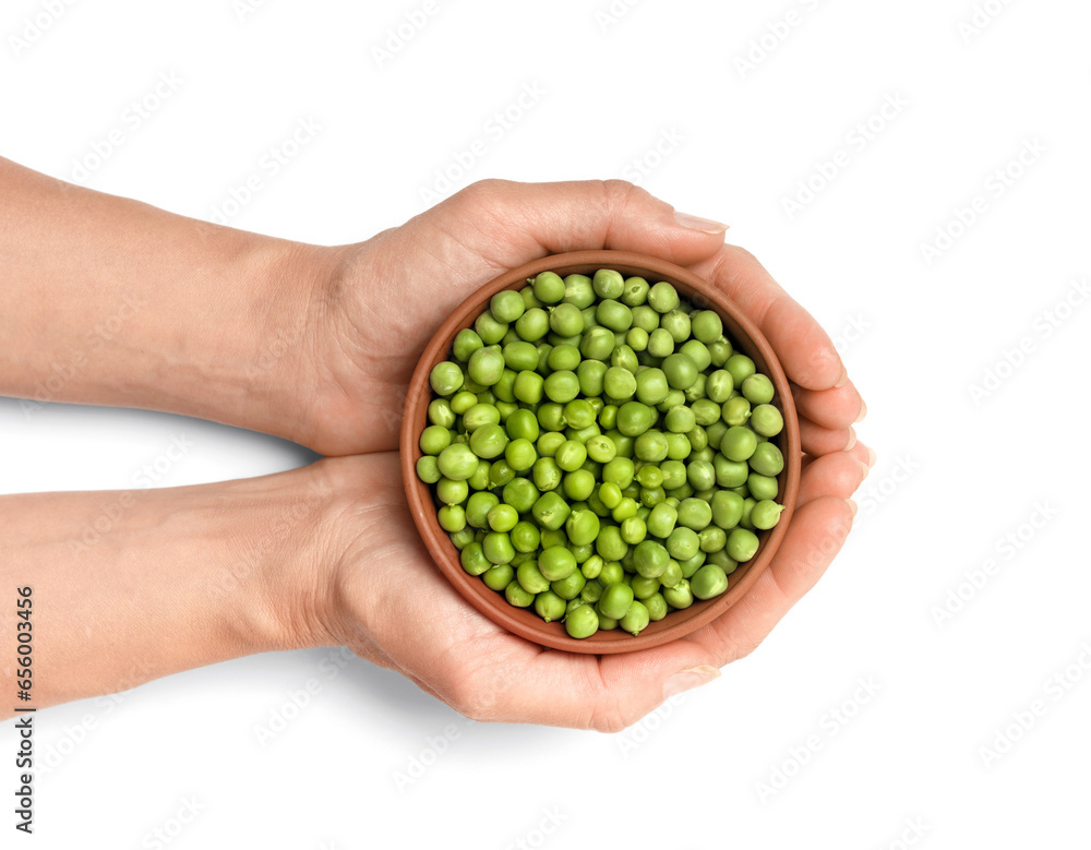 Peeled grains of green peas in a ceramic bowl in hands on a white background, top view.