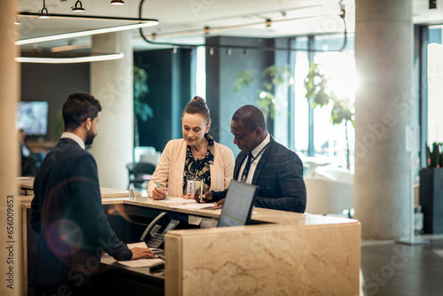 Two diverse business people signing papers at the reception of a hotel