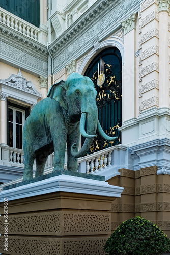 An imposing statue of an elephant commands attention as it rests upon an intricately designed base, positioned in front of a lavishly embellished building.