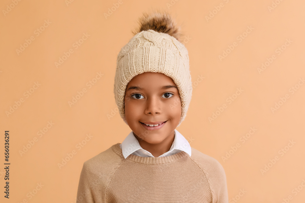 Cute African-American boy in warm winter clothes on beige background Cute African-American boy in warm winter clothes on beige background