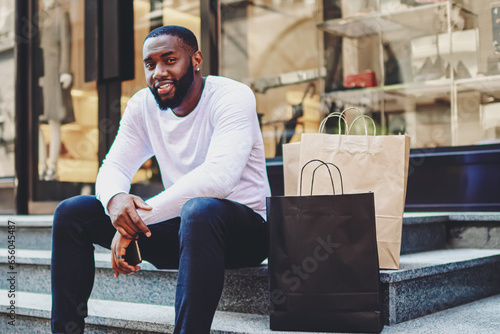 smiling dark skinned guy looking at camera enjoying recreation after buying purchases
