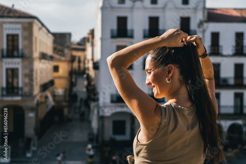 close up portrait of beautiful woman on a balcony terrace in sunlight while looking at the city, urban tourism