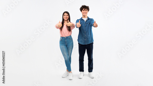Full length of girlfriend and boyfriend gesturing thumbs up, studio
