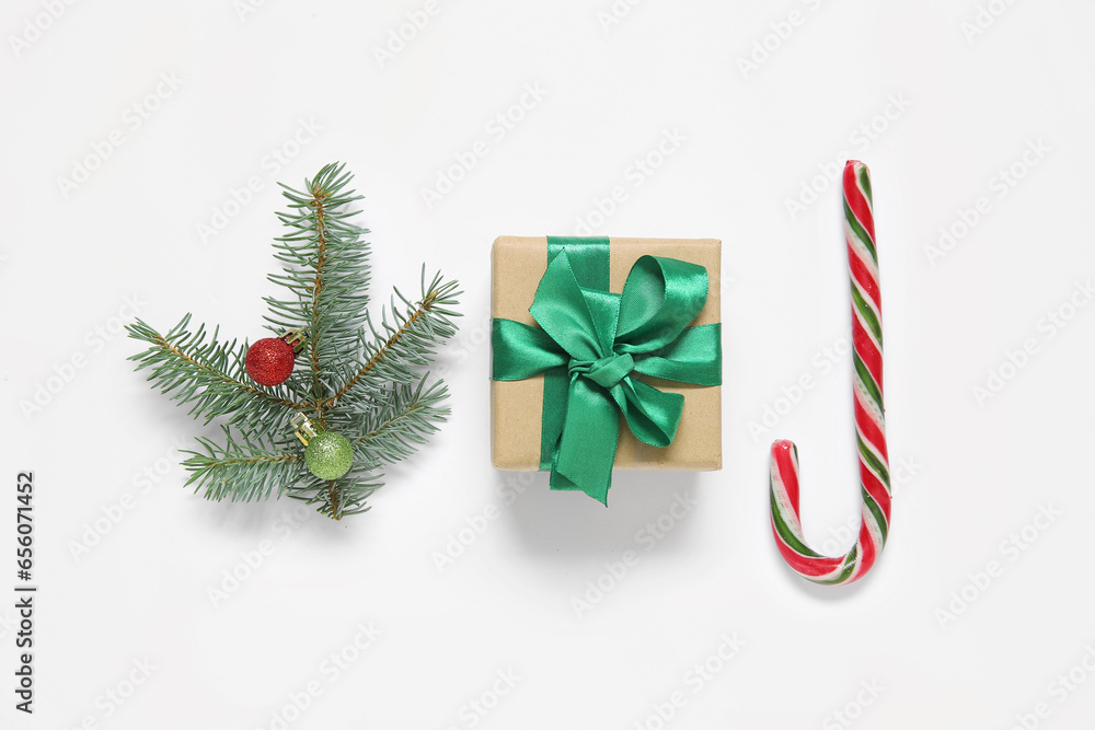 Gift box, fir branch with Christmas balls and candy cane on white background