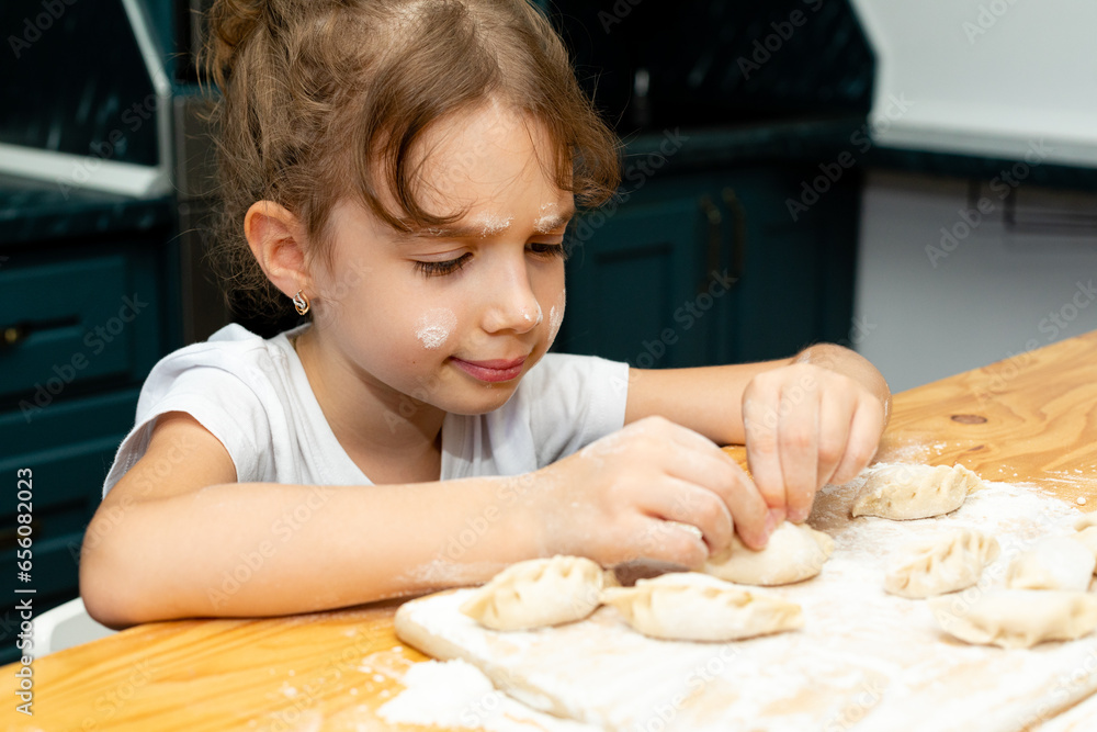Mom's little helper. Cute little girl in flour sculpts dumplings. Girl makes dumplings for dinner. Child helps in the kitchen for mom, kitchen, eggs, flour