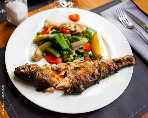 Appetizing grilled trout with stewed vegetables and a slice of lemon