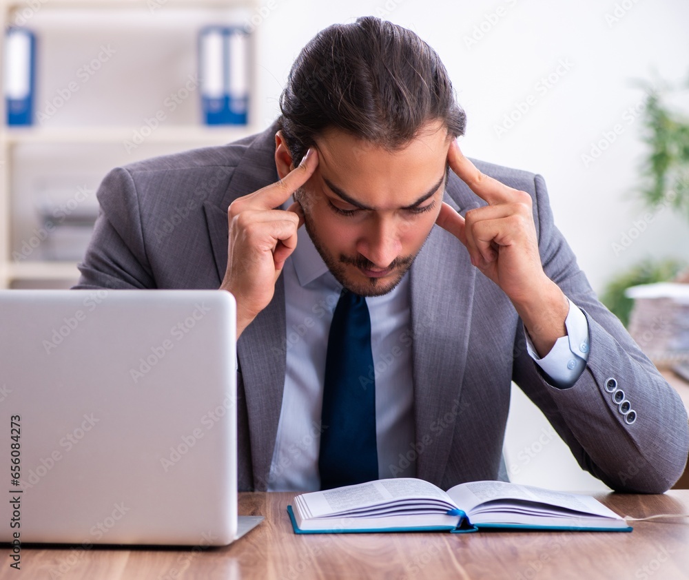 Young male businessman reading books at workplace Young male businessman reading books at workplace