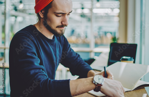 caucasian man in stylish apparel making notes of information in notepad for education