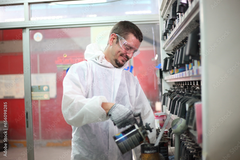 Auto mechanic working in garage. Repair service. Worker mechanics in uniform are working in auto service with lifted vehicle. Car repair maintenance.