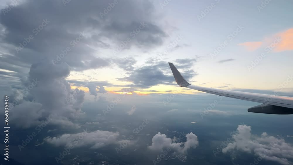Wing of flying above soft fluffy clouds airplane as seen by passenger through porthole. Wide view Wing of flying above soft fluffy clouds airplane as seen by passenger through porthole. Wide view