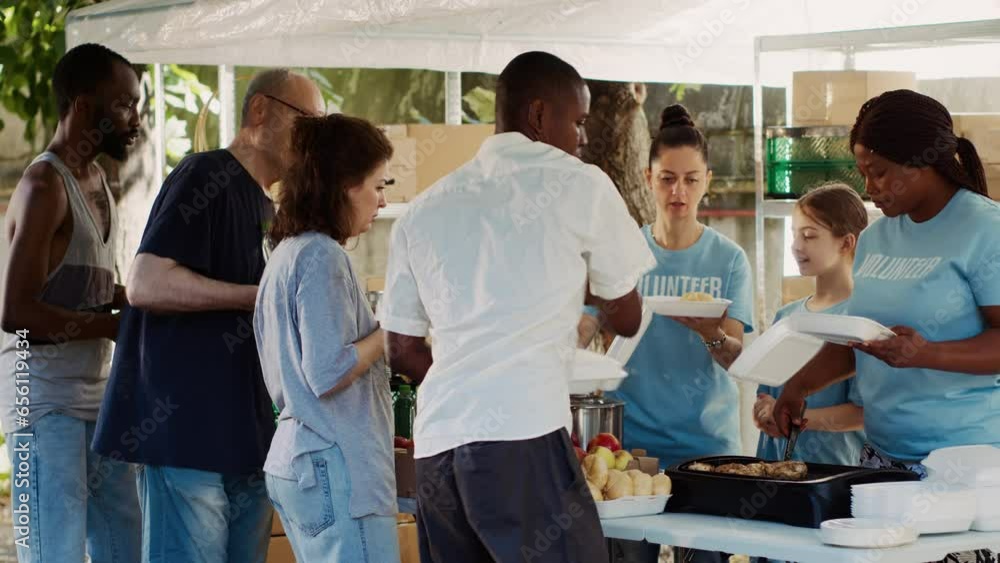 Outdoor food distribution event organized by a non-profit, drawing people of all races who want to help the homeless and less fortunate. Warm meals are provided by volunteers to the poor and needy.