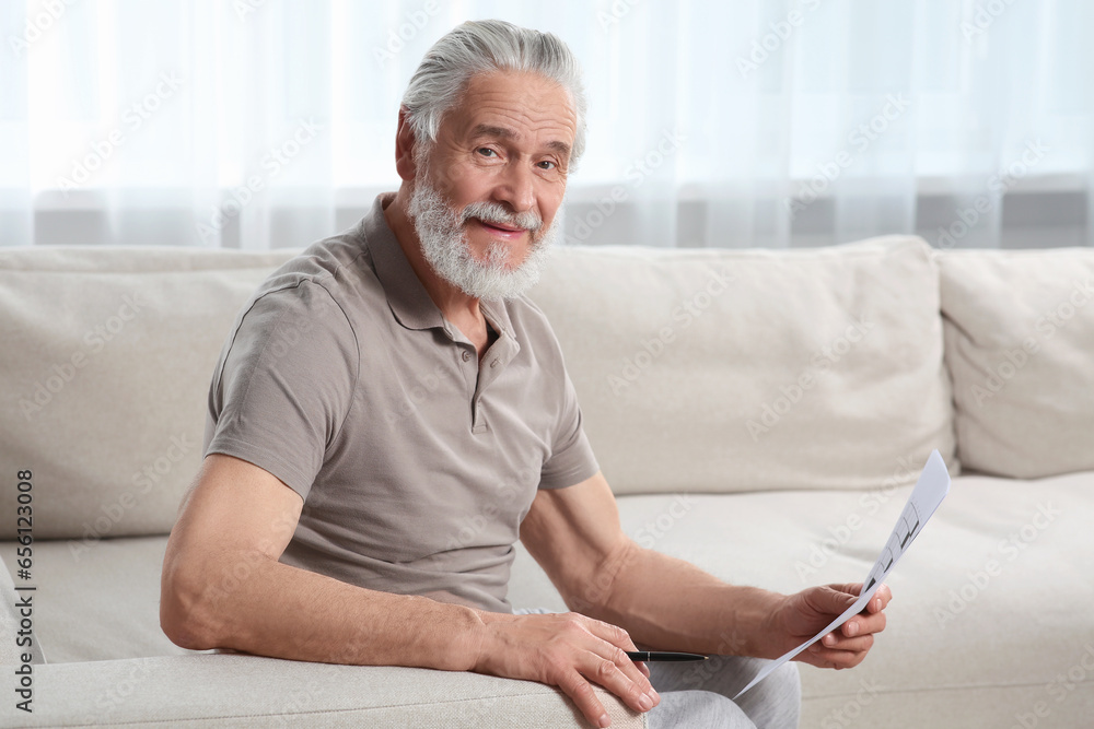 Senior man solving crossword on sofa at home Senior man solving crossword on sofa at home