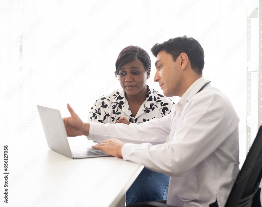 Hispanic physician check-up African American patient with stethoscope at the hospital. Healthcare medical diagnosis and examining on the laptop. Hispanic physician check-up African American patient with stethoscope at the hospital. Healthcare medical diagnosis and examining on the laptop.