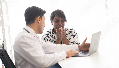 Hispanic physician check-up African American patient with stethoscope at the hospital. Healthcare medical diagnosis and examining on the laptop.