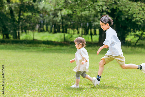 公園で追いかけっこする活発な子供達・兄妹・走る・短距離走 